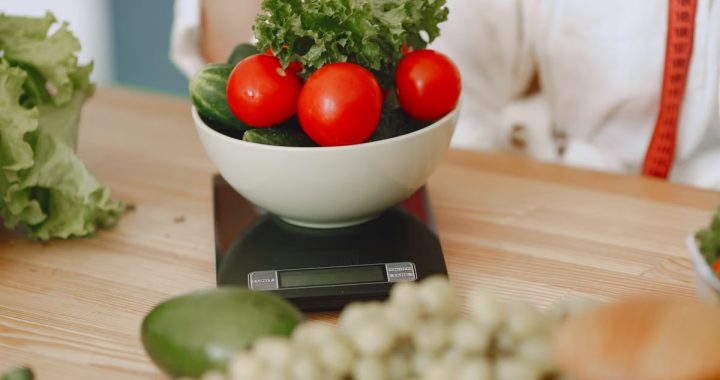 Colorful fresh vegetables including tomatoes and cucumbers on a kitchen scale for healthy eating.